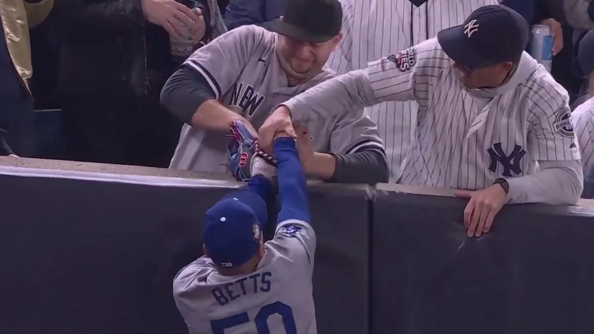 Dos fanáticos luchan por una bola tras un espectacular salto del jugador.